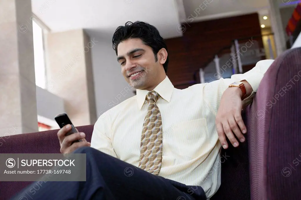 Businessman using cell phone on sofa