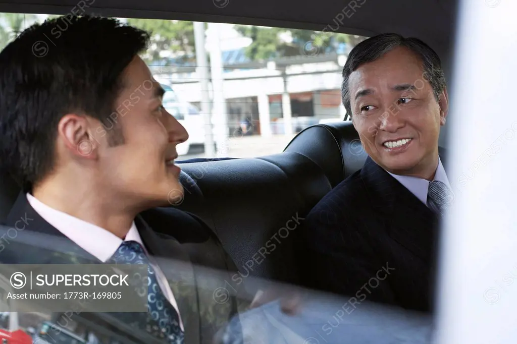 Businessmen riding together in taxi