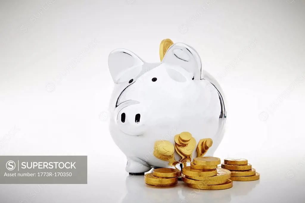 Stack of gold coins by piggy bank