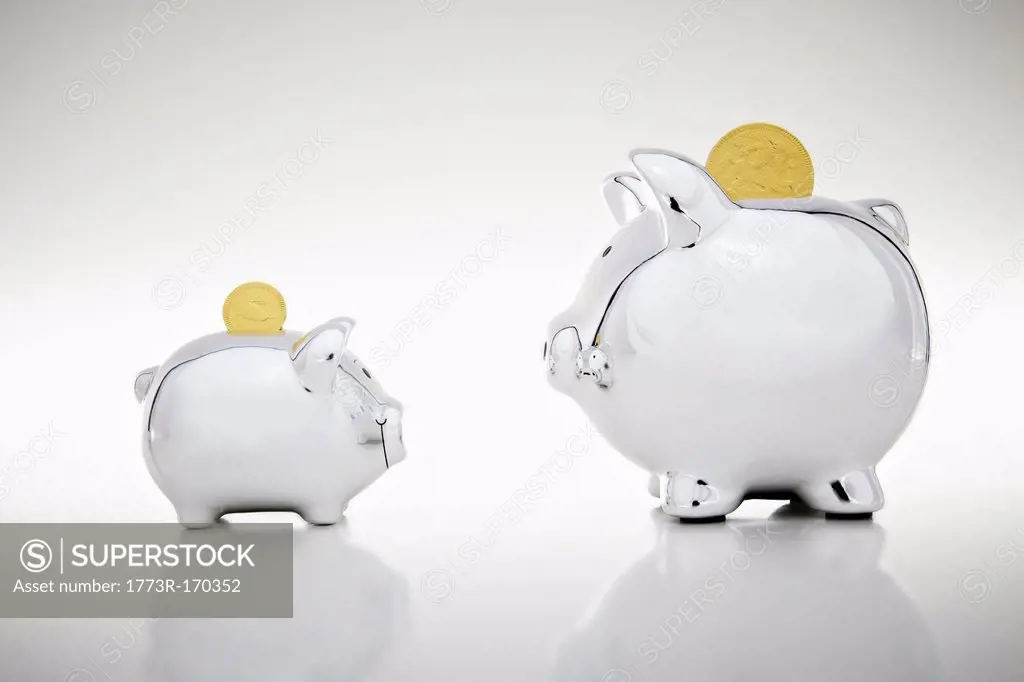 Gold coins dropping into piggy banks