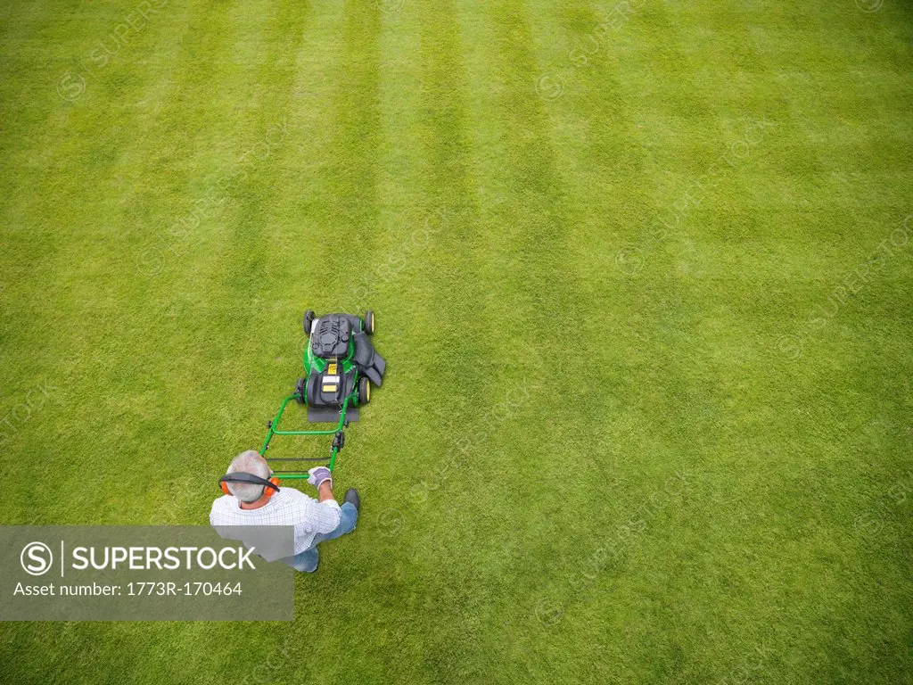 Man wearing headphones and mowing lawn