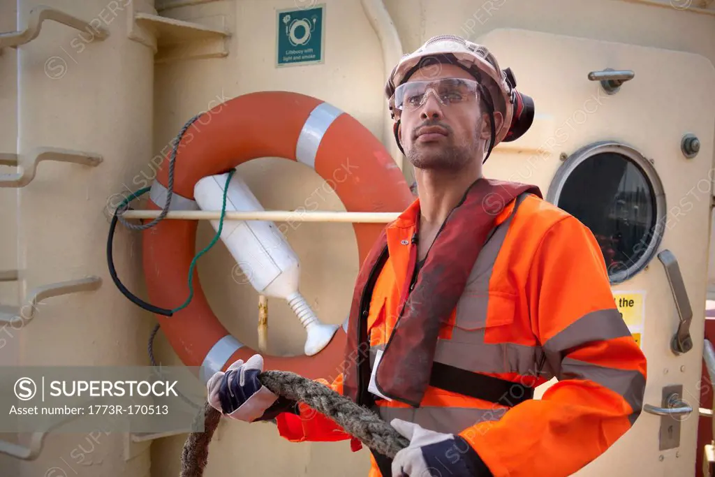 Tugboat worker holding rope on deck