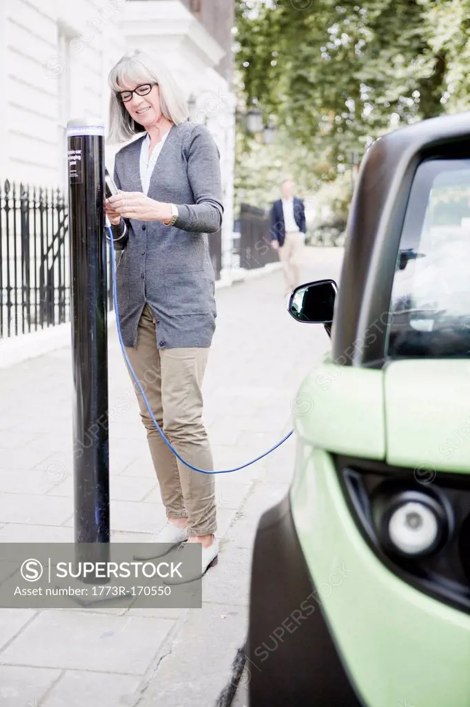 Woman charging electric car on street