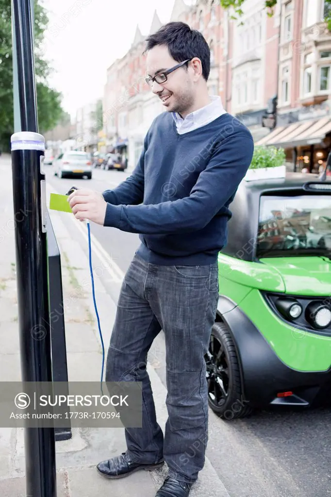 Man charging electric car on street
