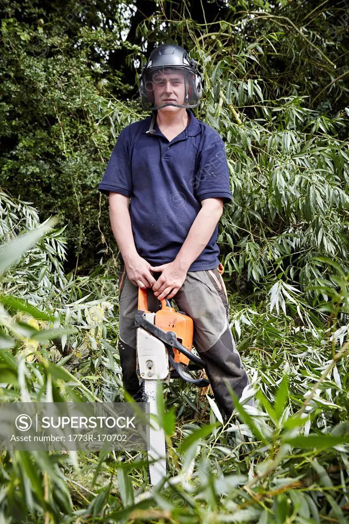 Worker holding chainsaw in forest