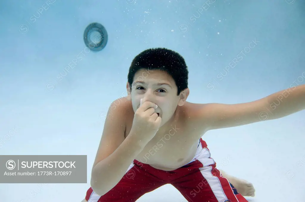 Boy holding nose underwater