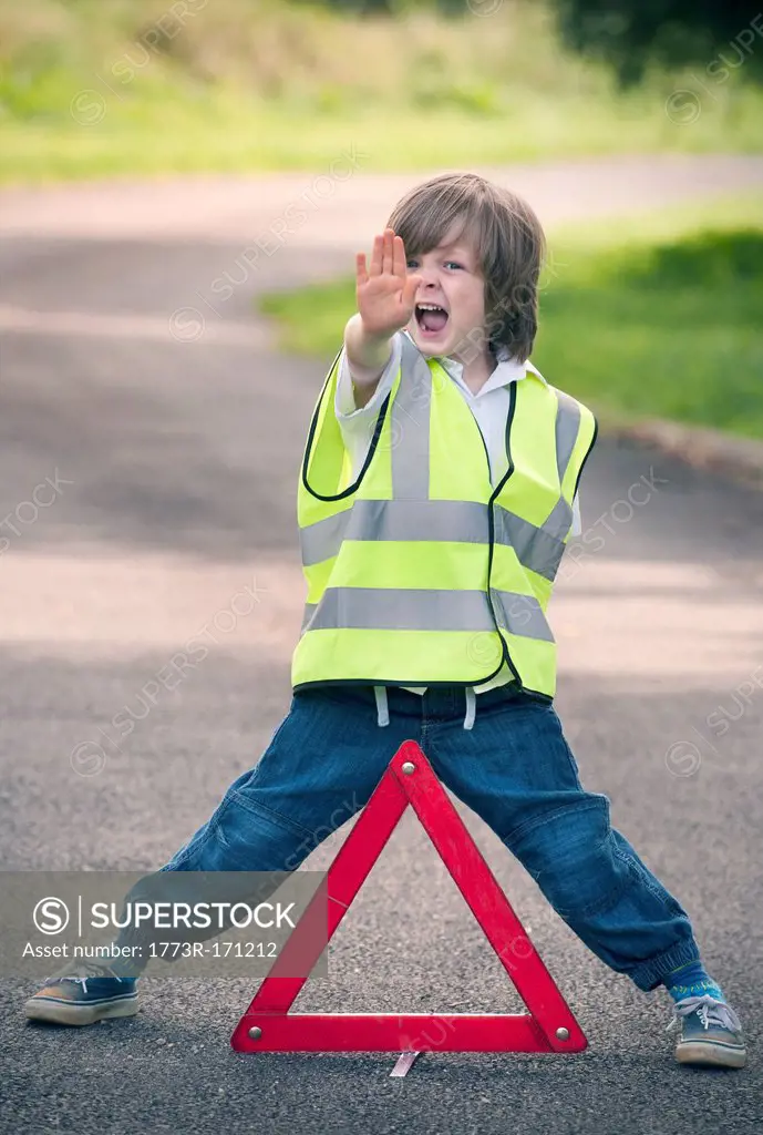 Boy playing traffic worker on rural road