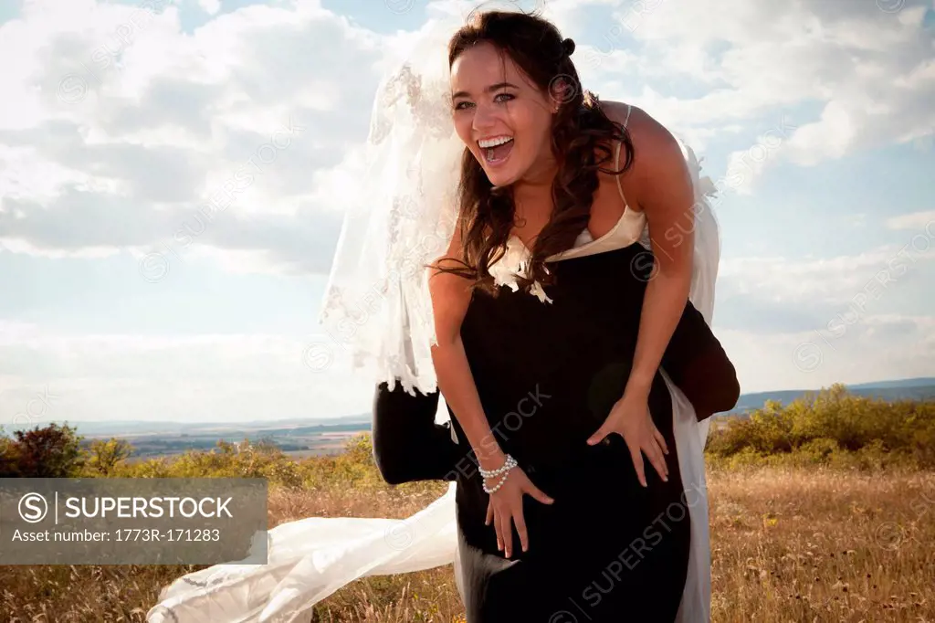 Newlywed groom carrying bride outdoors