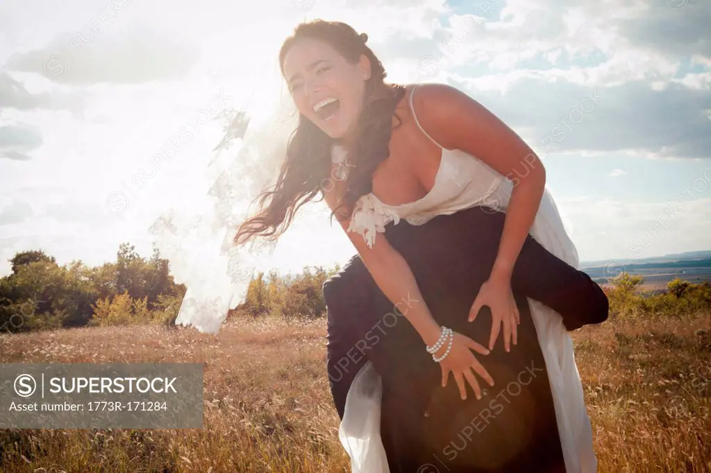 Newlywed groom carrying bride outdoors