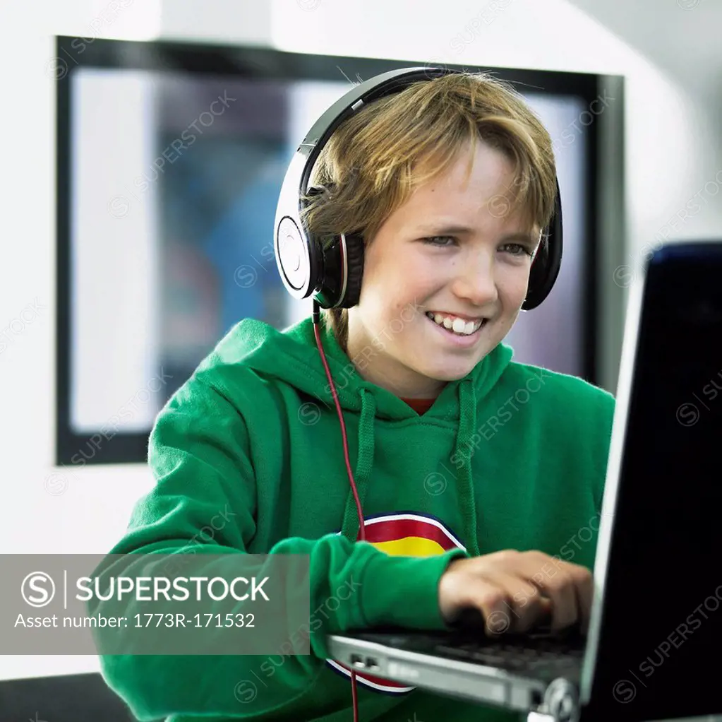 Boy wearing headphones on laptop