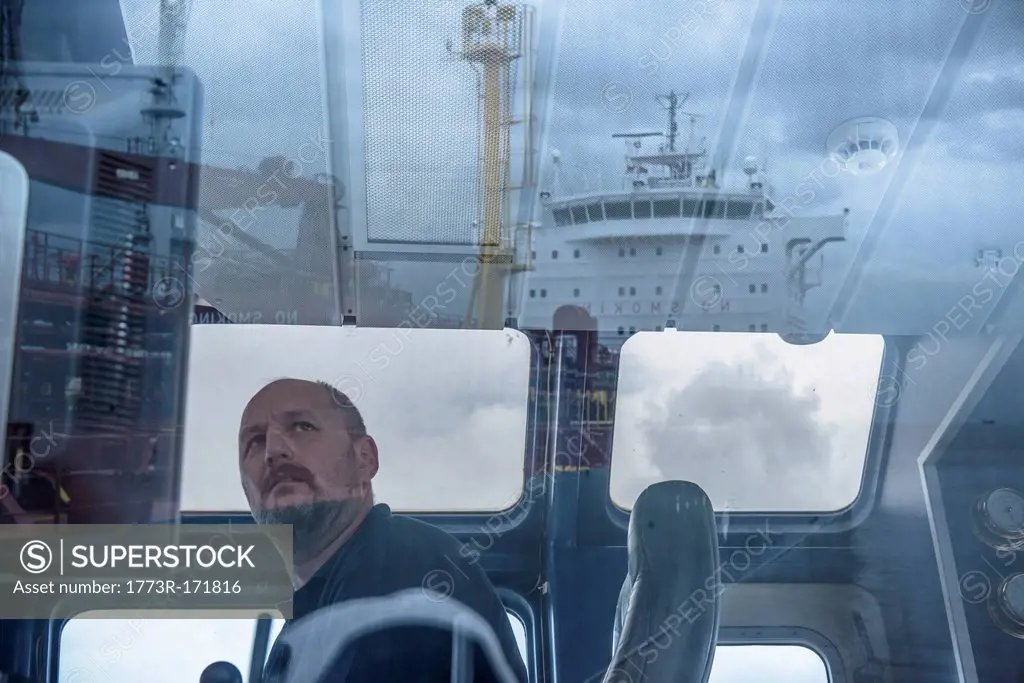 Worker in tugboat wheelhouse at window