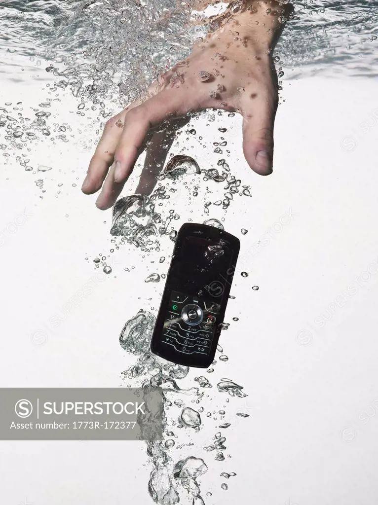 Hand grasping cell phone in water