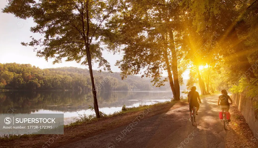 Couple riding bicycles by river bank