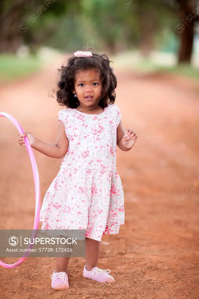Girl playing with hula hoop on dirt road
