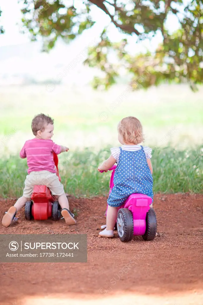 Toddlers riding toys on dirt road
