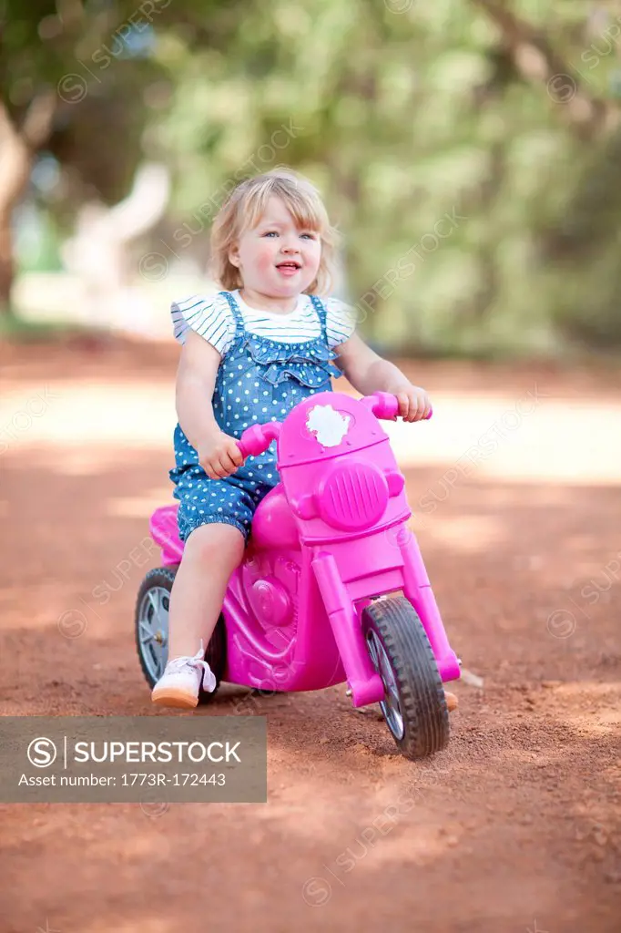 Toddler girl riding toy on dirt road