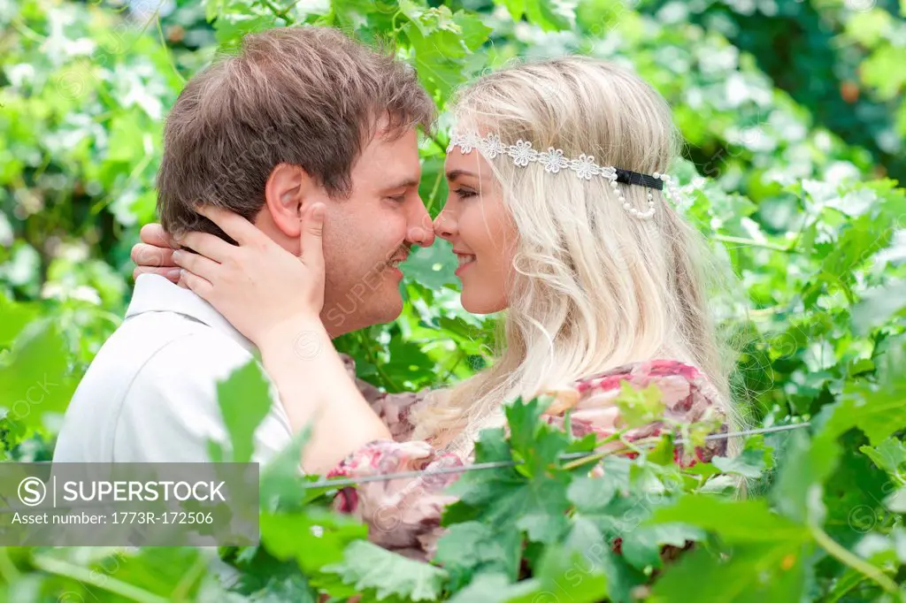 Couple touching noses in tall plants