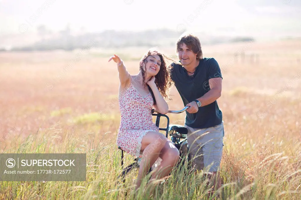 Couple playing on bicycle in tall grass