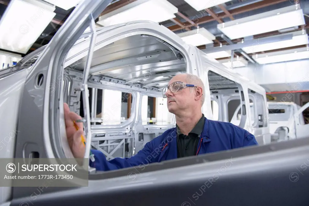 Worker inspecting car in factory