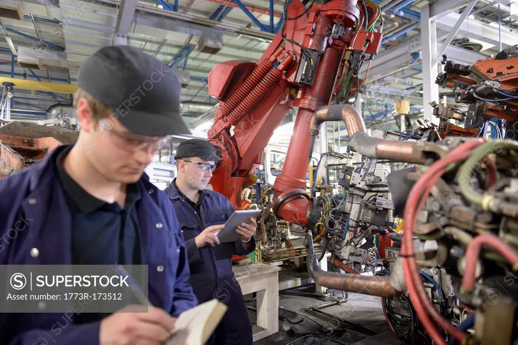 Apprentices with robots in car factory