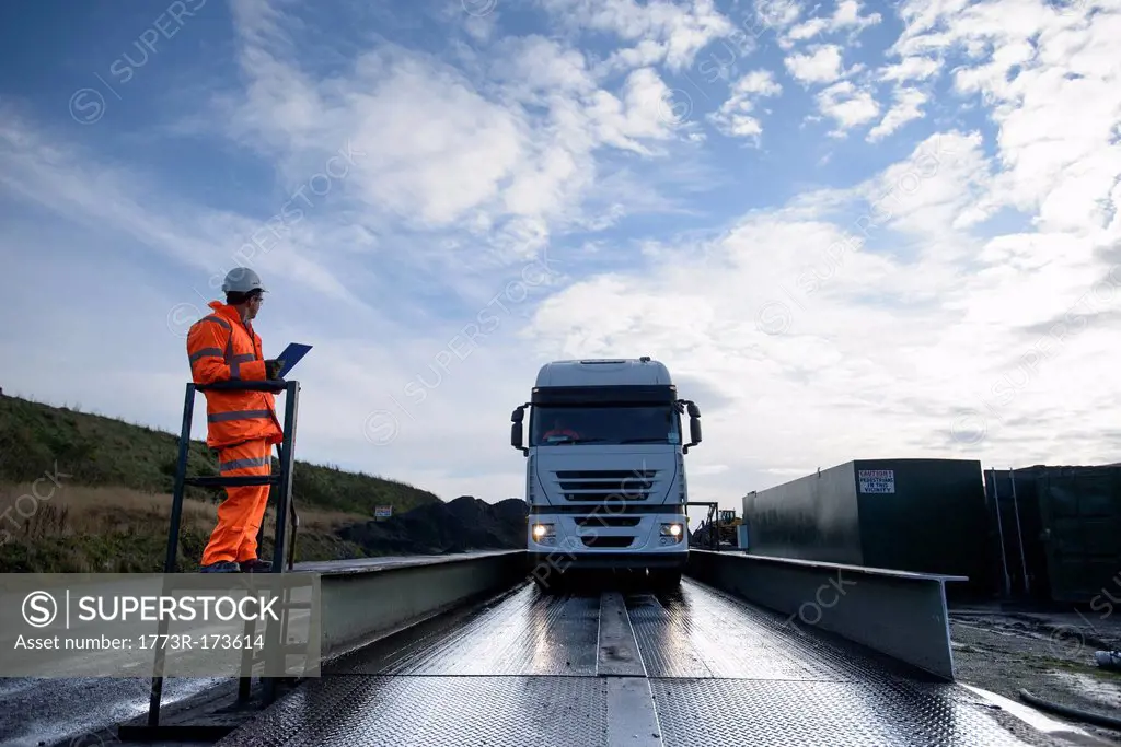 Worker directing truck on scales