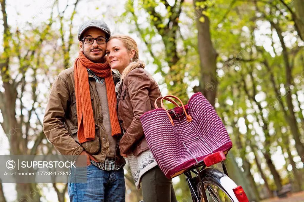 Couple hugging by bicycle in forest