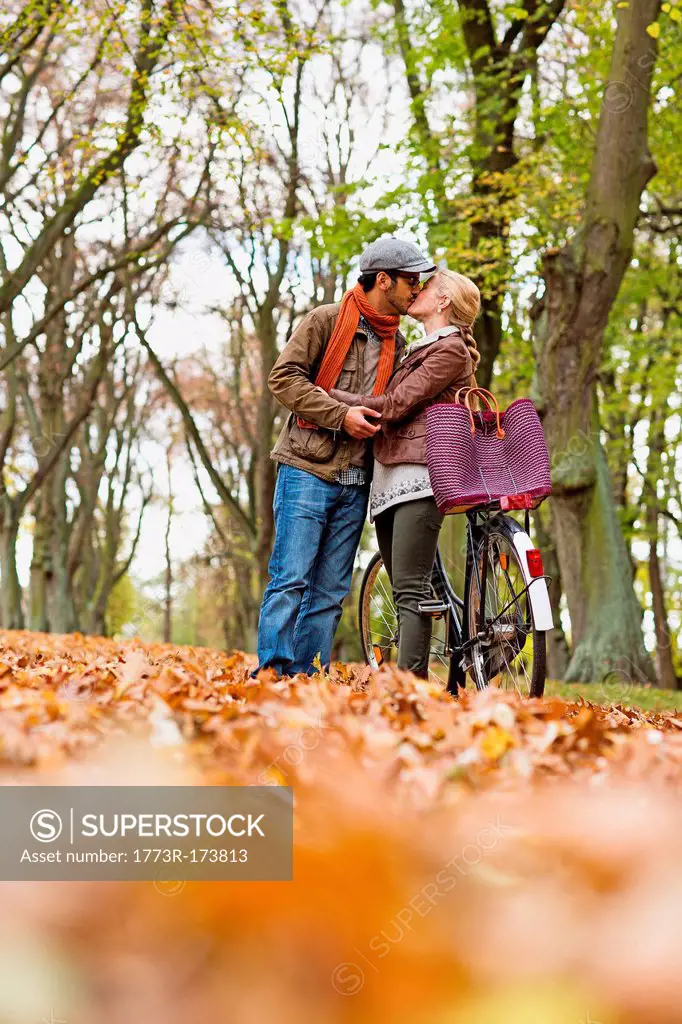 Couple kissing by bicycle in forest