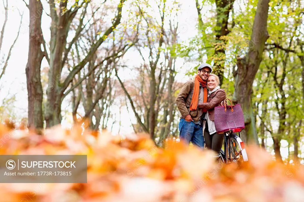 Couple hugging by bicycle in forest