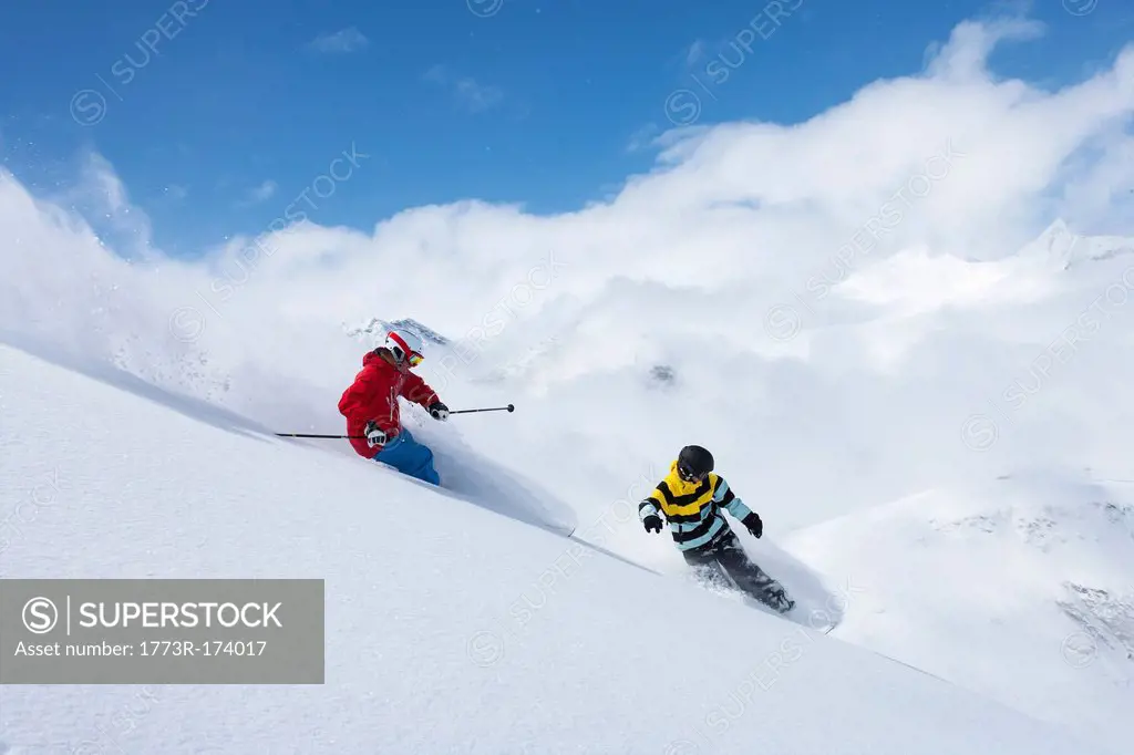 Skier and snowboarder on snowy slope