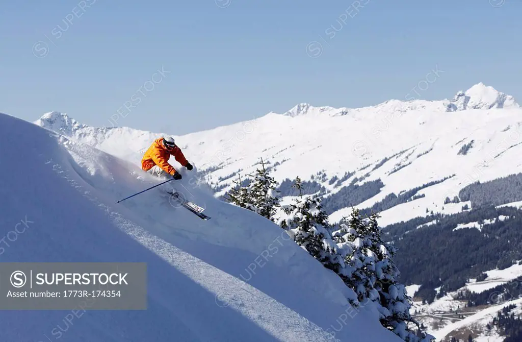man skiing down slope, mountains in distance