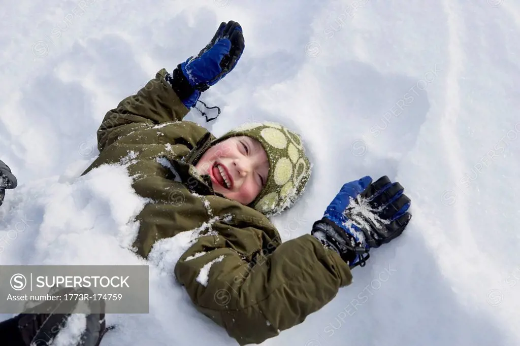 Young boy lying in snow