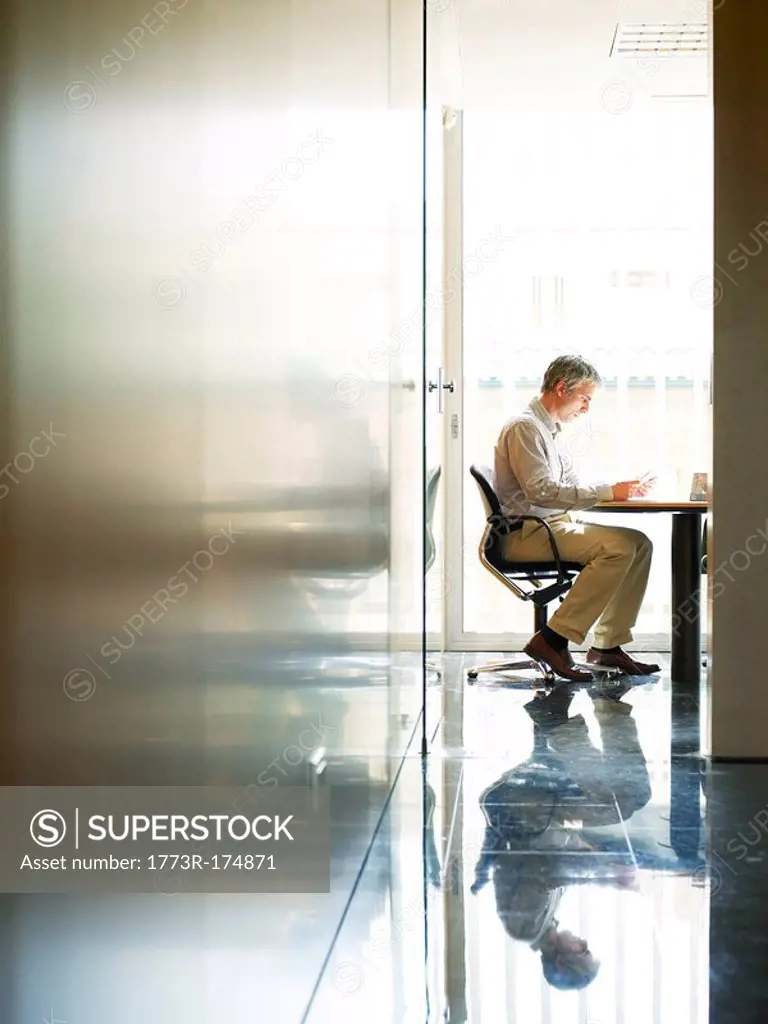 Businessman sitting at table in office, side view