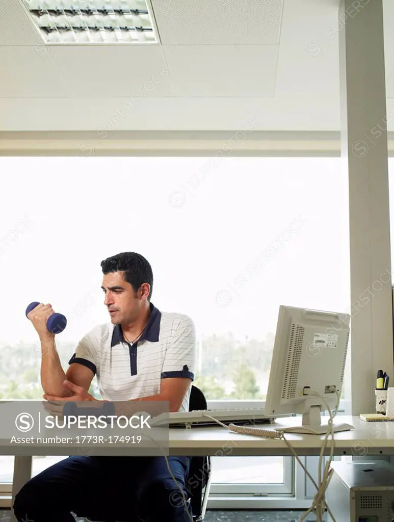 Man sitting at desk lifting weights