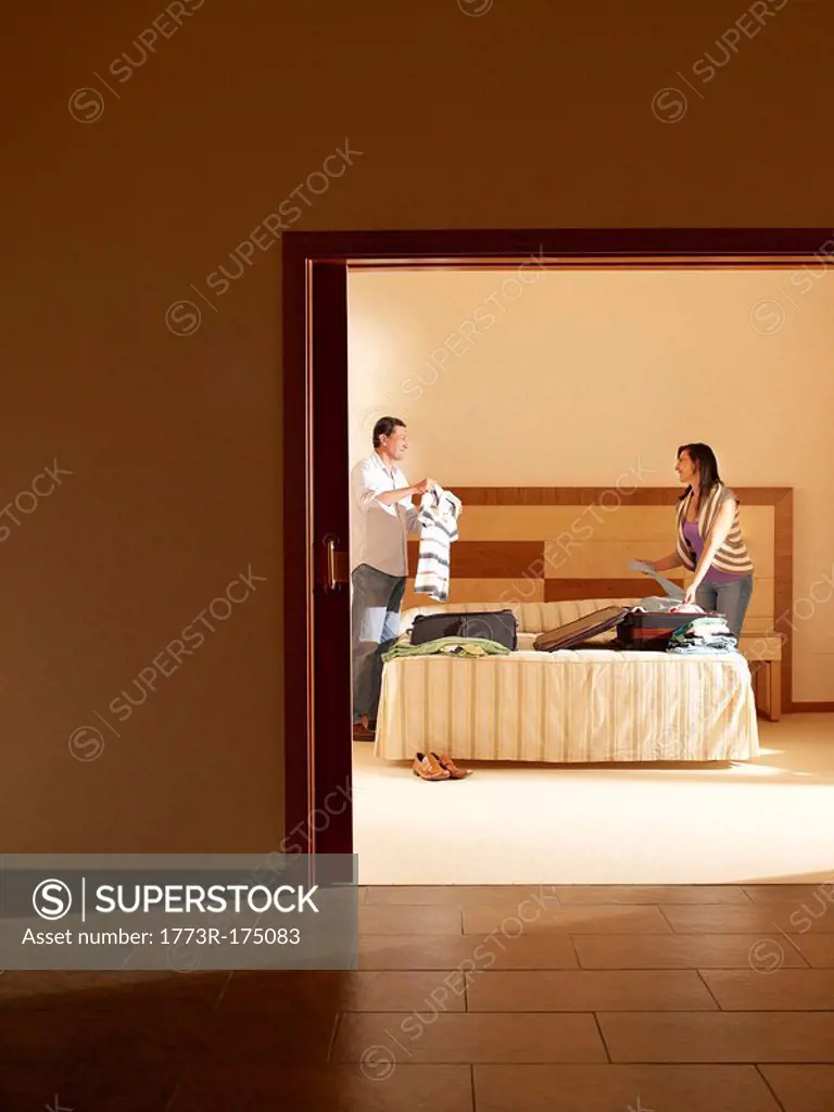 Couple unpacking suitcases in hotel room