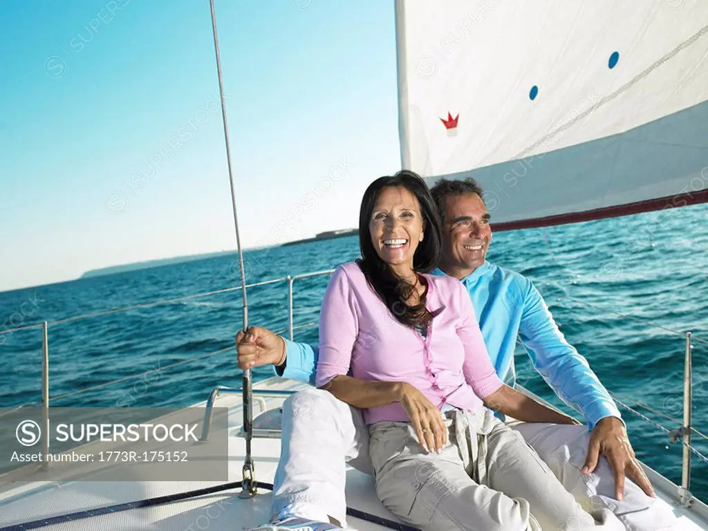 Mature couple sitting on deck of yacht, smiling, portrait
