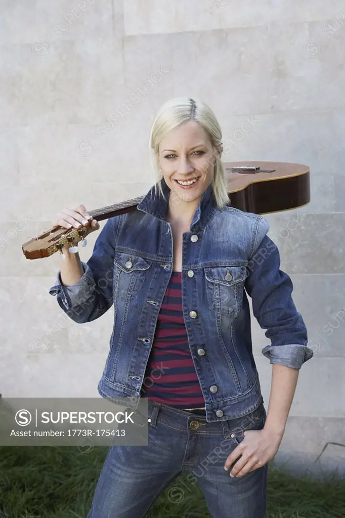 Woman standing holding a guitar smiling