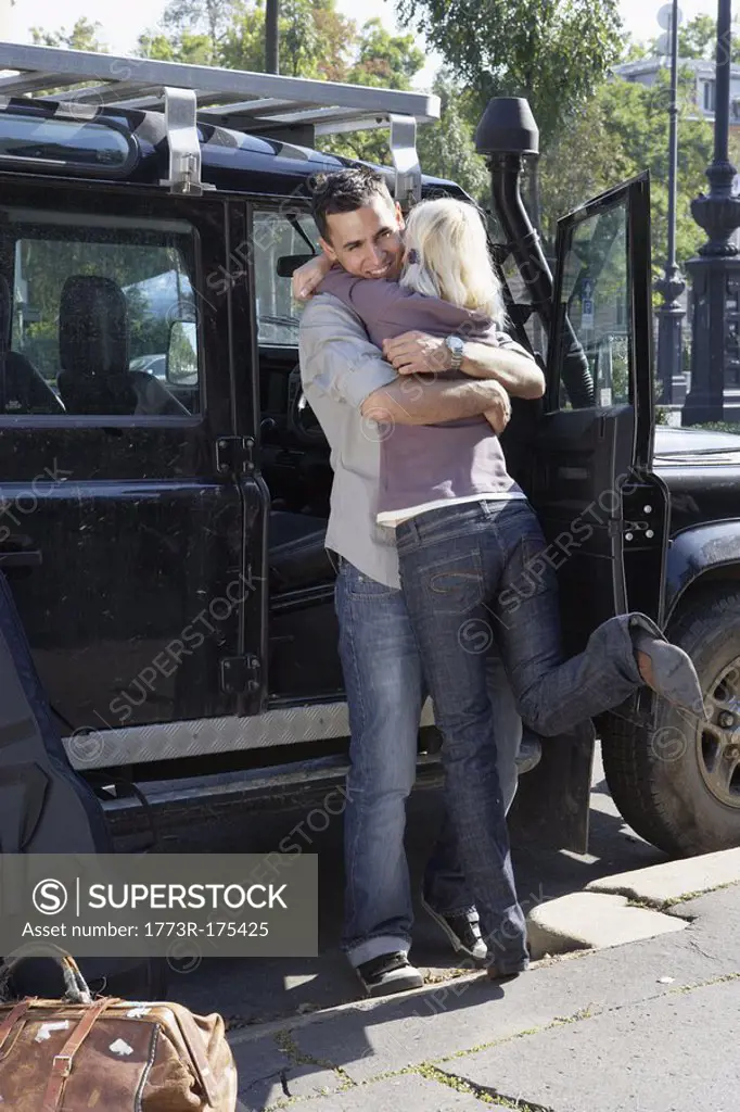 Couple embracing by an SUV smiling