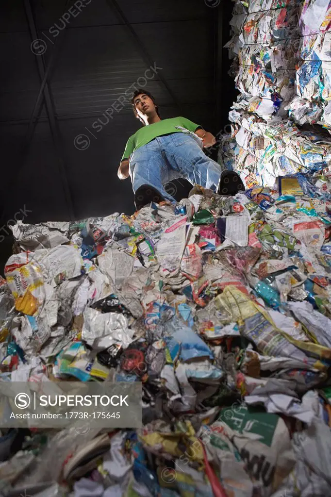 Man standing on top of a wall of recycling