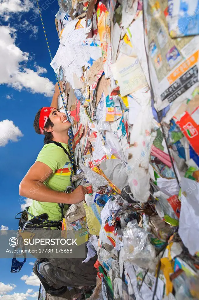Man climbing a wall of recycling