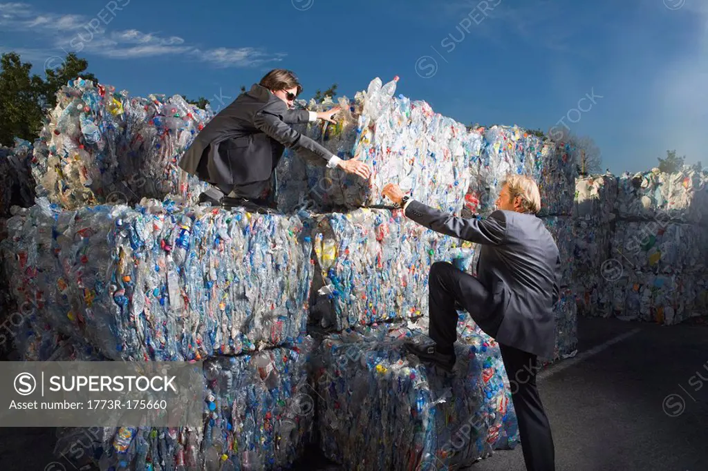 Businessmen climbing a wall of recycling