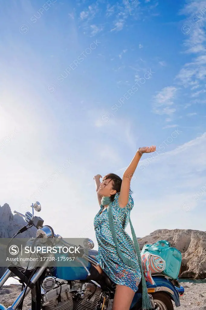 Woman on motorbike arms aloft