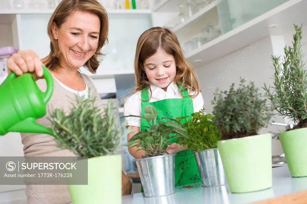 Daughter and mother watering herbs