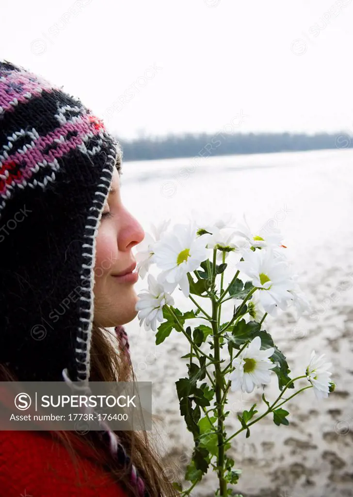Young woman outdoors smelling flowers, eyes closed, close-up
