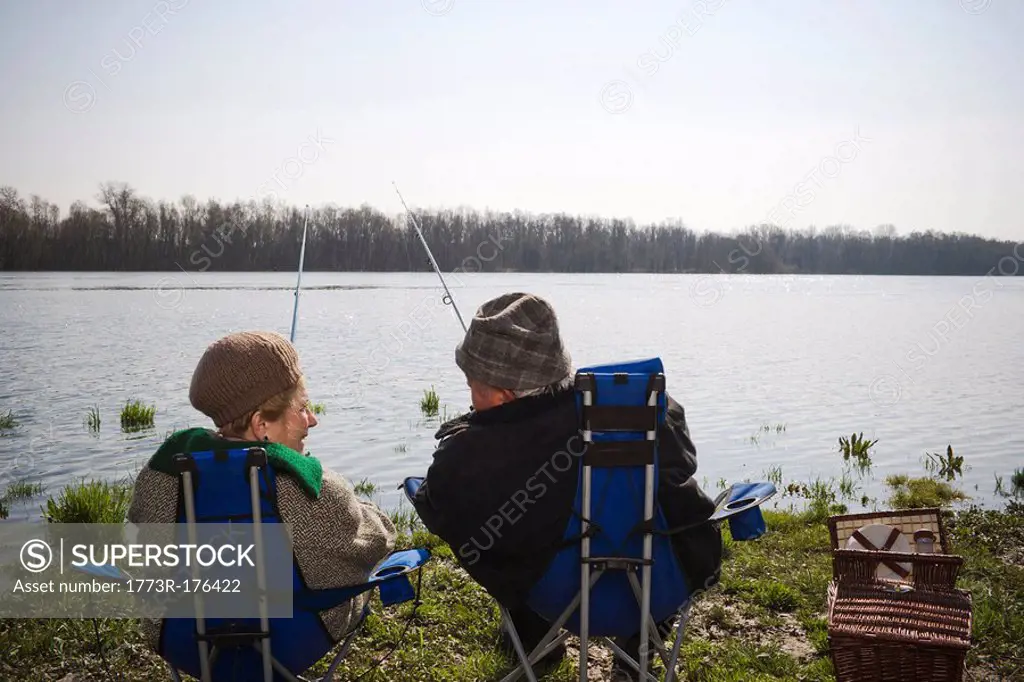 Senior couple fishing together by river, rear view