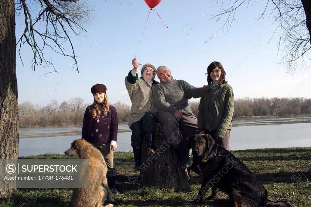 Grandparents, grandson 12-14 and granddaughter 10-12 with two dogs by river