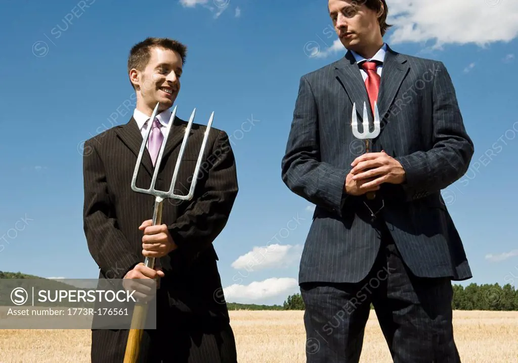 Two men holding garden tools next to each other