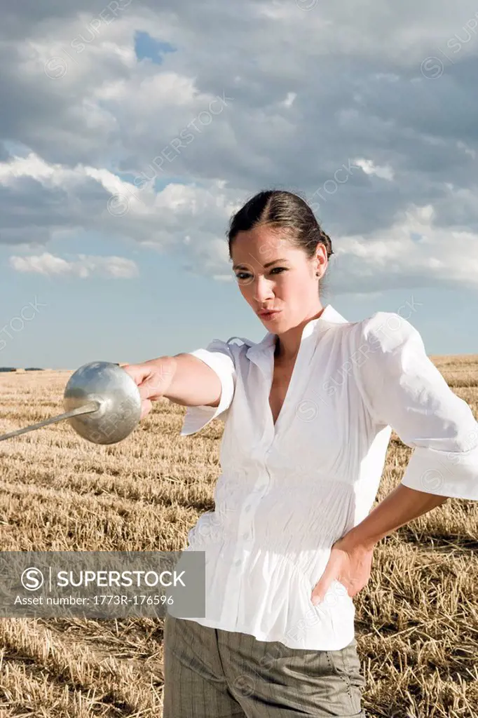 Woman pointing sword in wheat field