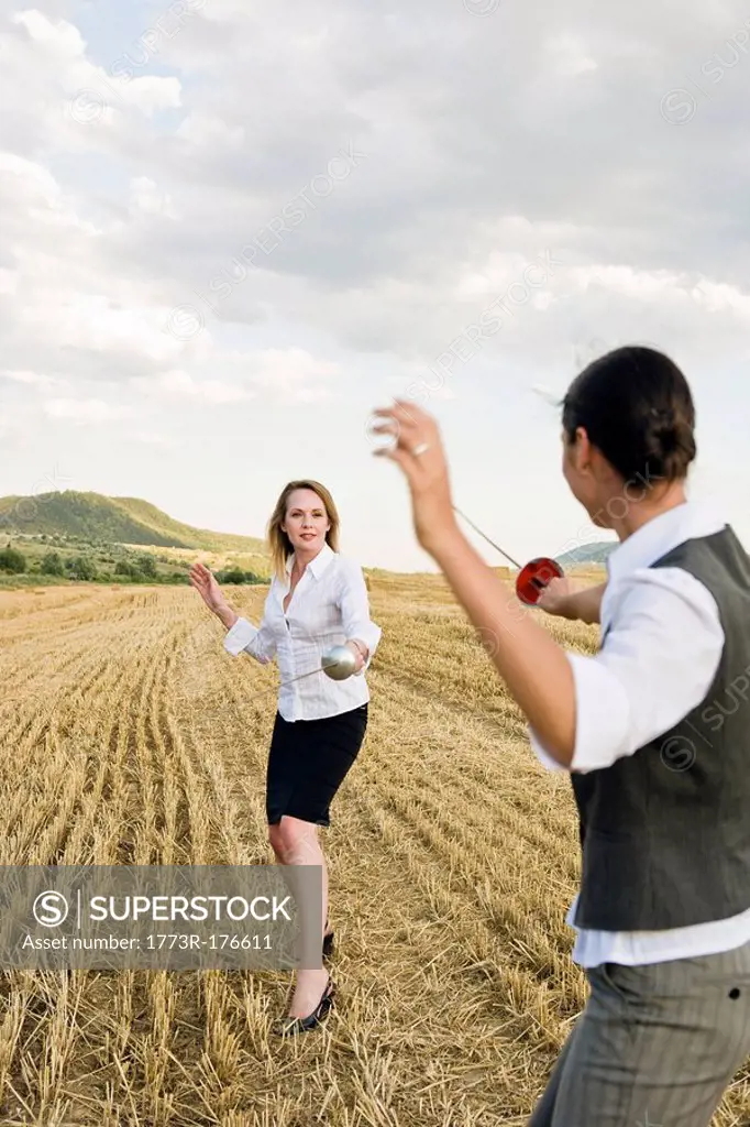 Businesspeople fencing in a wheat field
