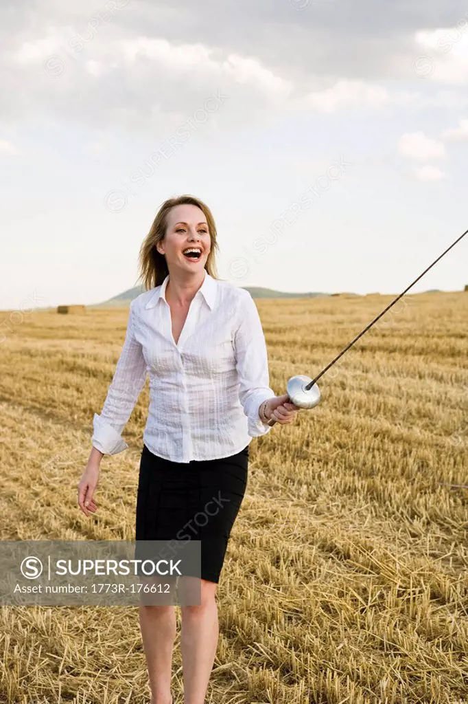 Businesswoman fencing in a wheat field