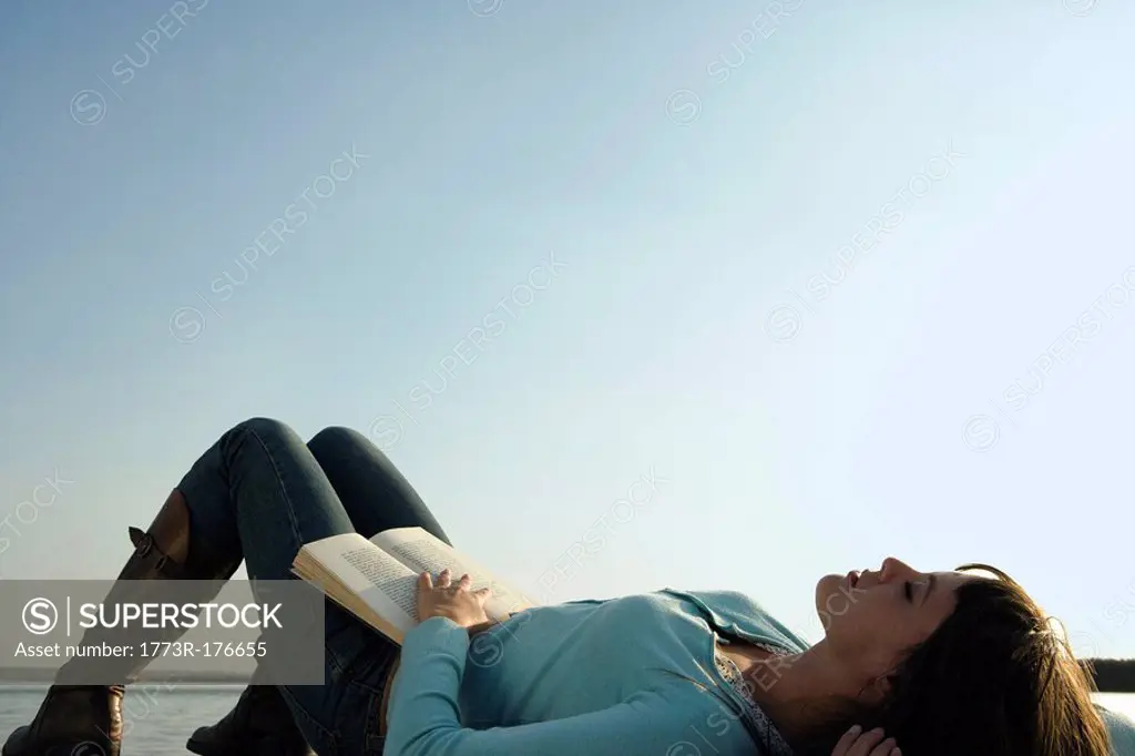 Woman lying on her back with a book